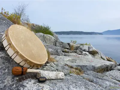 indigenous drum with baton on rock overlooking the water