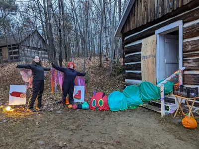 Two people with arms open outside a decorated house