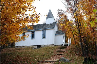 exterior autumn image of a white church with steeple, titled Wesley Methodist Church