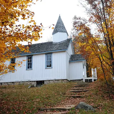 exterior autumn image of a white church with steeple, titled Wesley Methodist Church