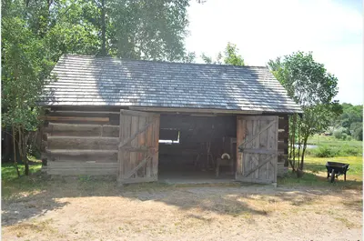 exterior log workshop with doors open, called Watson Workshop